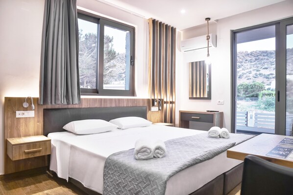 A hotel room with a bed, a desk, and a view of the outdoors.