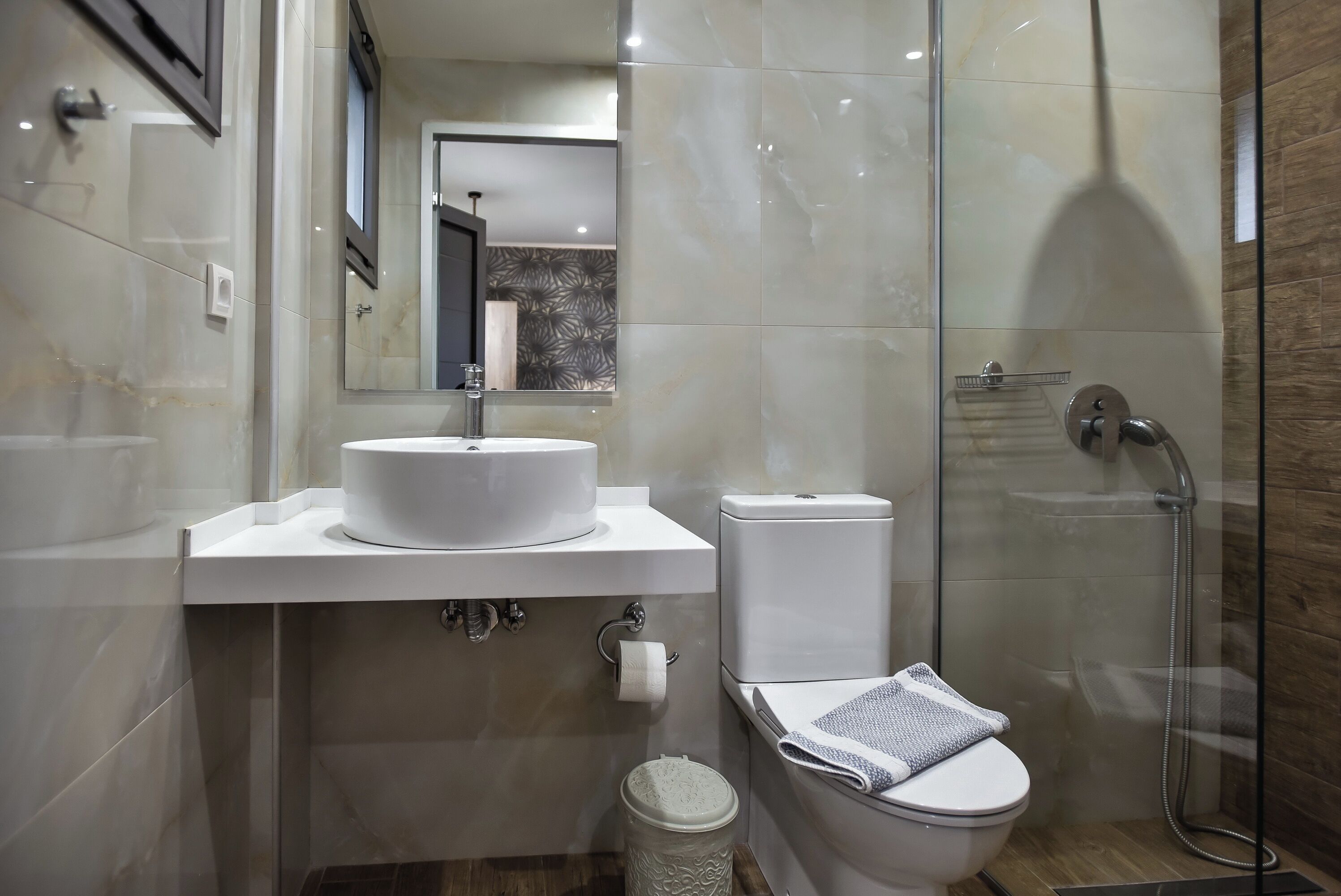 A modern bathroom with a white sink, toilet, and glass-enclosed shower.