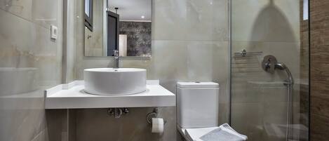 A modern bathroom with a white sink, toilet, and glass-enclosed shower.