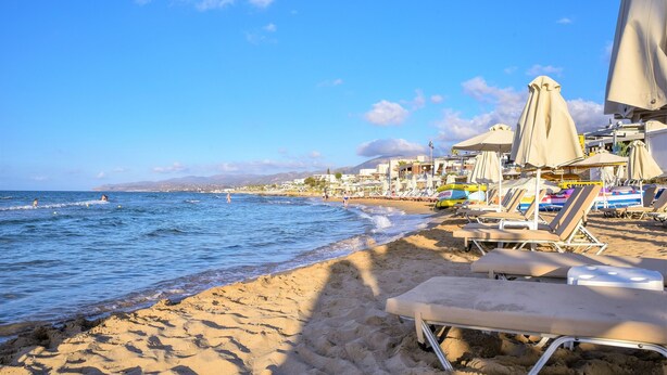 A beach with sun loungers and umbrellas, a clear sky, and the ocean. - Del Mar Apartments in Stalis (Hersonissos)