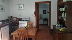 A compact kitchen with a dining table, chairs, a stove, and a cabinet with dishes. - A comfortable, private, country apartment. 300mts walk to safe sandy beach. (Collingwood)