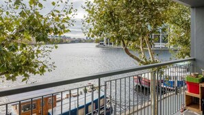 Un balcón con vista a un río, una embarcación amarrada cerca y una barandilla.