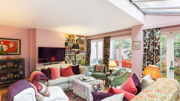 Ein gemütliches Wohnzimmer mit einer Couch, Sesseln, einem Couchtisch und einem Bücherregal.