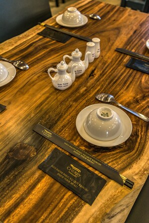 A wooden table with teapots, cups, and a spoon. There are also two black packets labeled "Cherry" and "Fan Hanh." - Cherry Hotel and Apartment (Ho Chi Minh City)