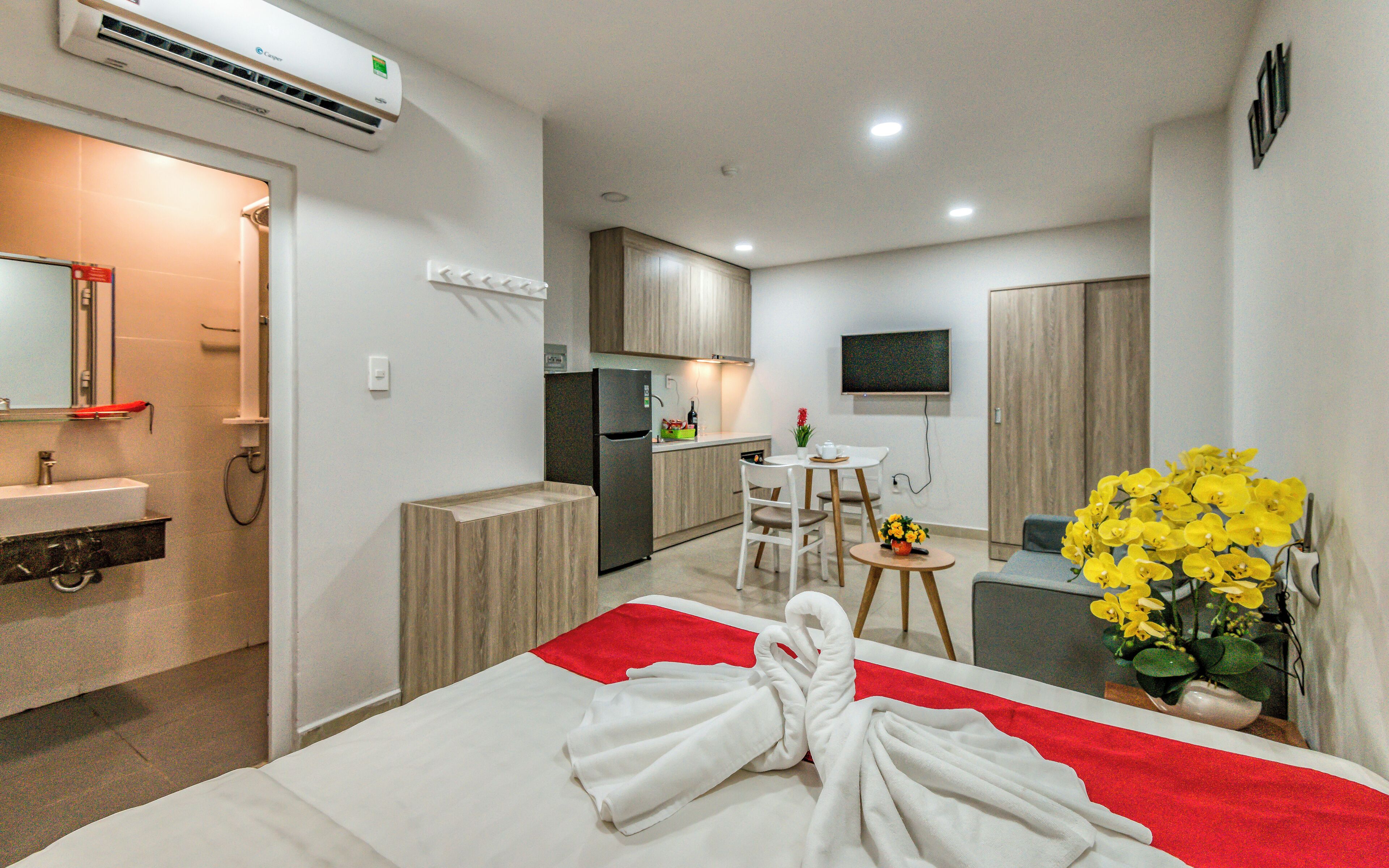 Habitación de hotel con cama, baño, kitchenette y televisor.