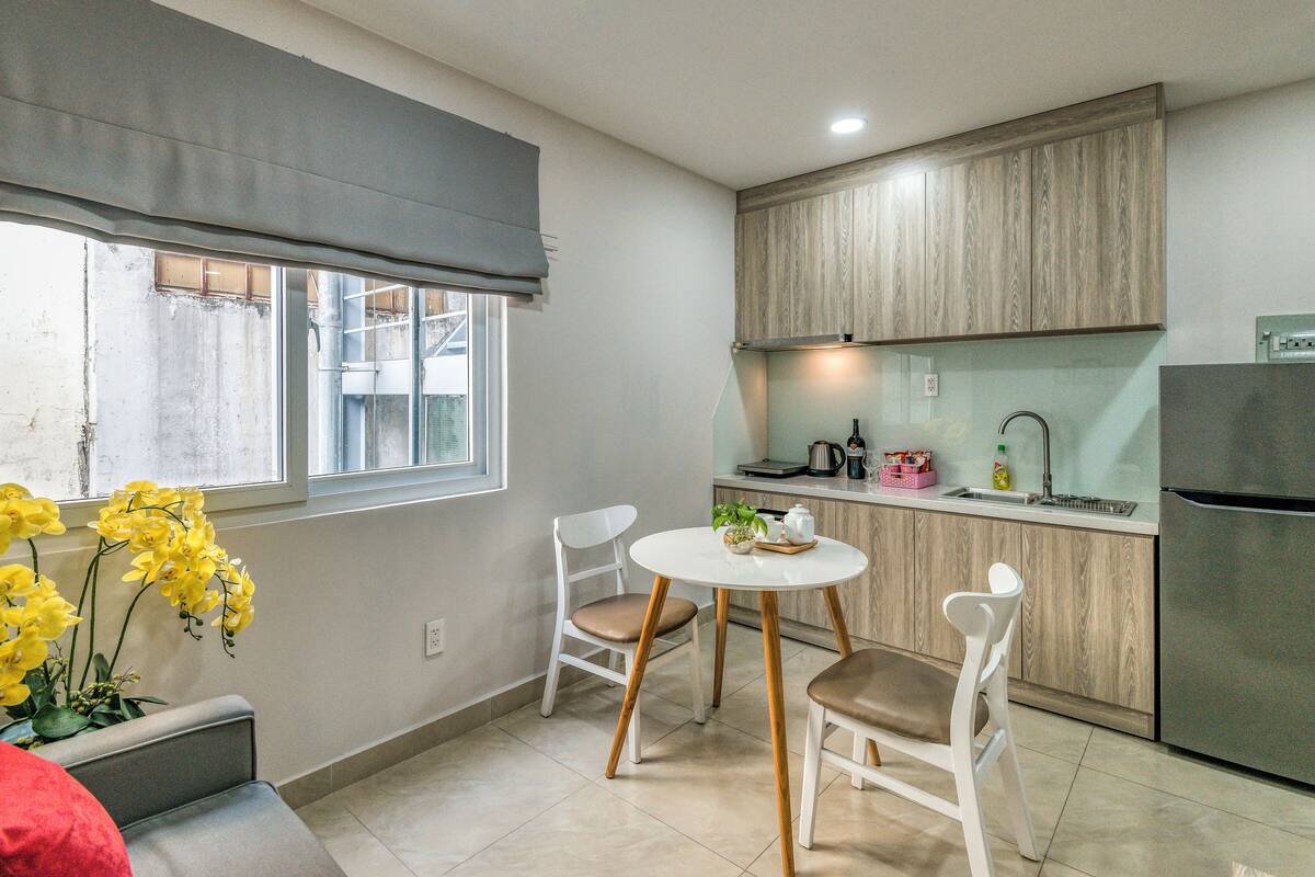 A compact kitchen with a dining area, featuring a window with a view, a refrigerator, and a sink.
