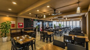 A restaurant with multiple tables and chairs, a black marble wall, and a large window providing a view.