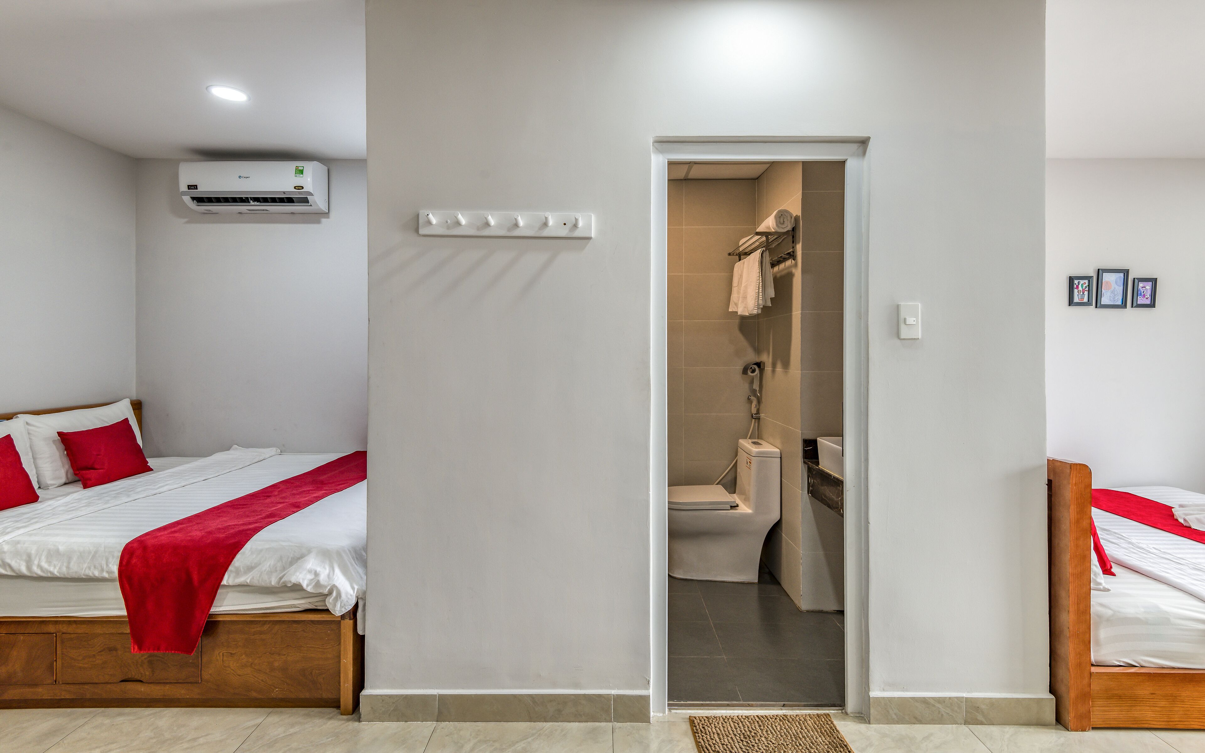 A hotel room with a bed, a bathroom visible through an open door, and a ceiling-mounted air conditioner.