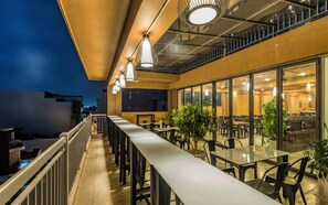An outdoor dining area with tables and chairs, a railing, and potted plants. - Cherry Hotel and Apartment (Ho Chi Minh City)