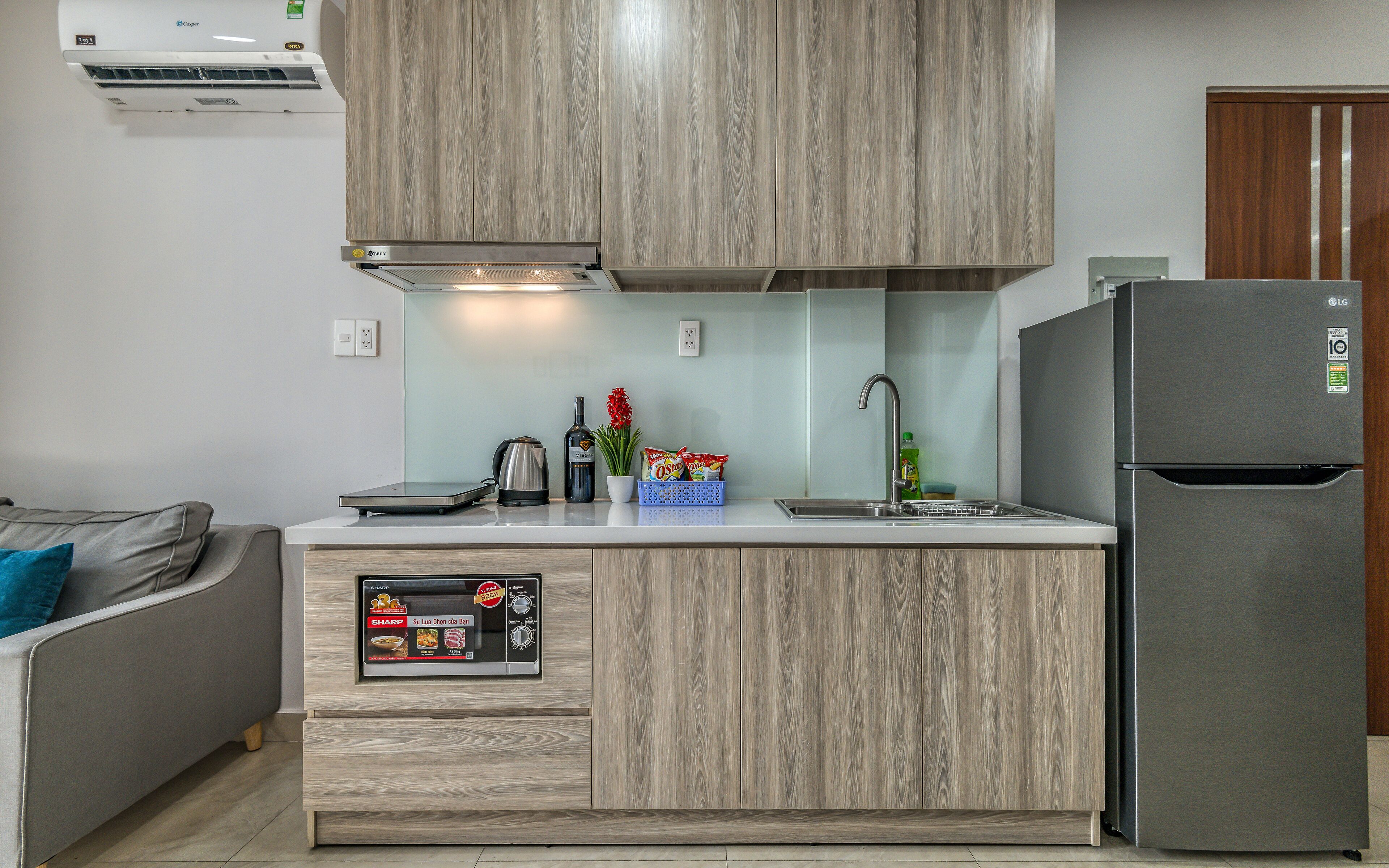 A modern kitchen with wooden cabinets, a built-in microwave, and a stainless steel refrigerator.