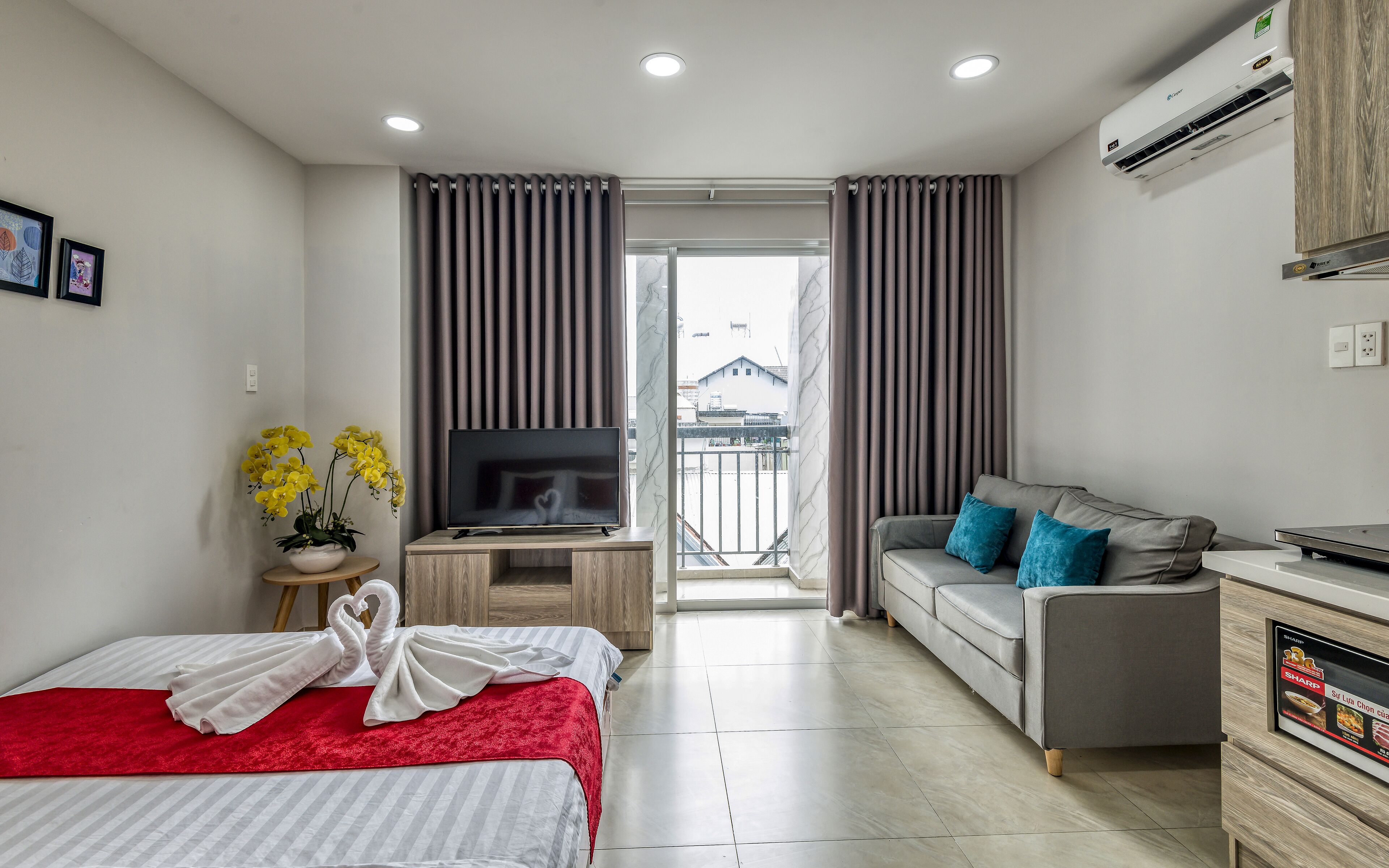 Ein modernes Hotelzimmer mit Bett, Fernseher, Sofa und Schreibtisch.