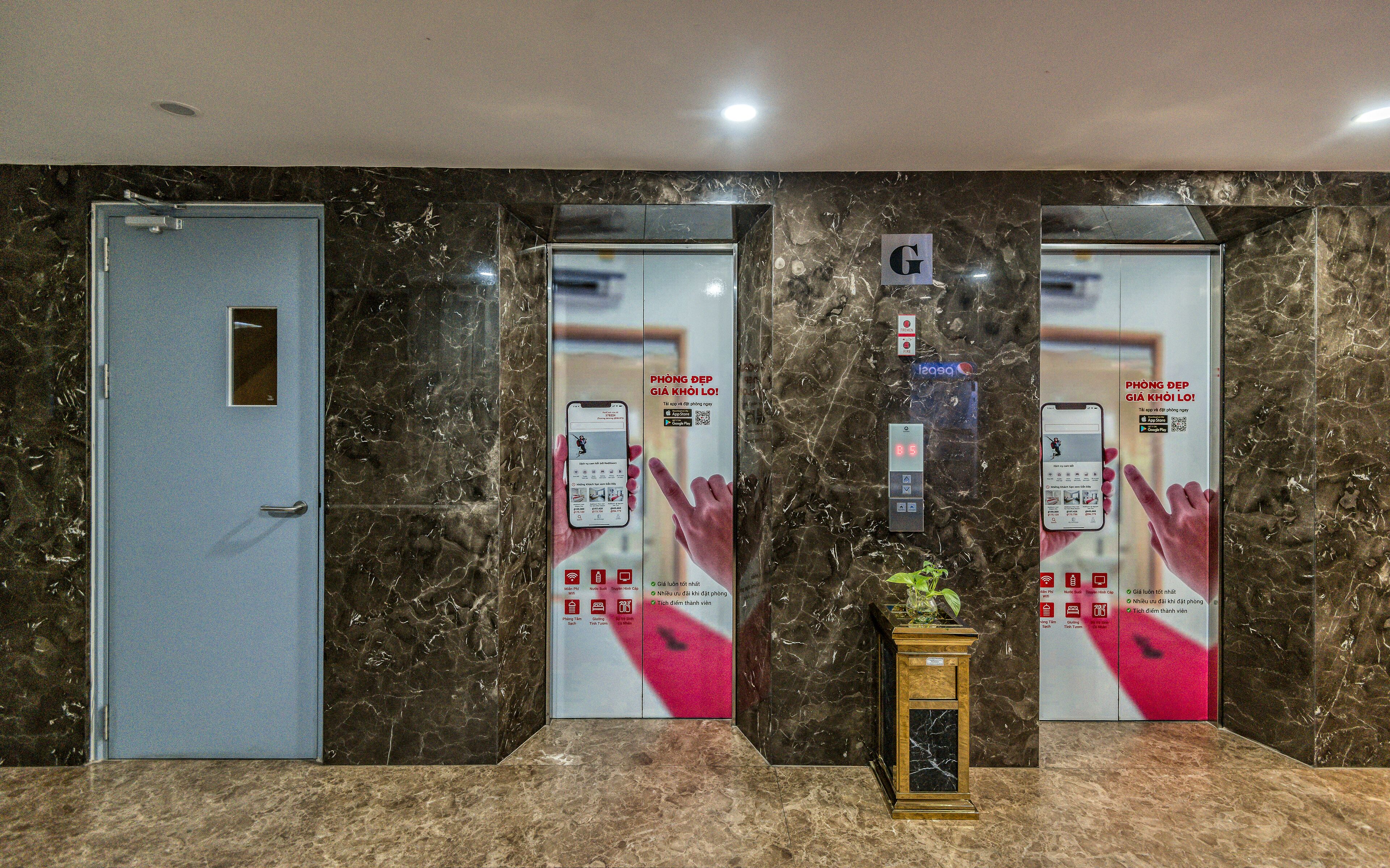 Un hall de hotel con paredes de mármol, dos ascensores y un mostrador de recepción.