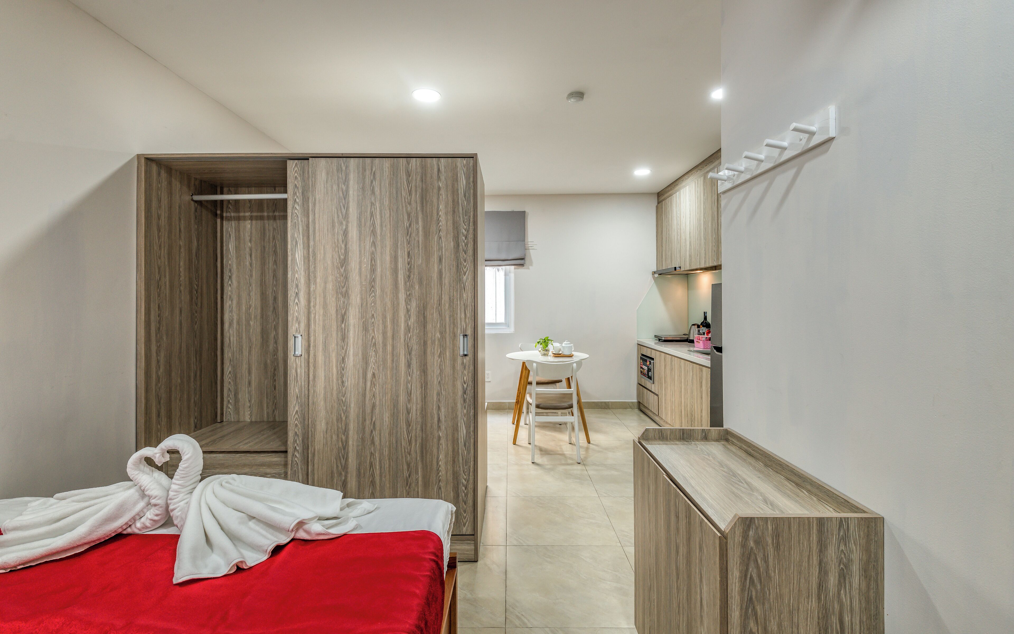 Una habitación de hotel moderna con cama, una mesita, kitchenette y baño.