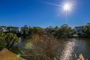 A residential area with houses along a body of water, reflecting sunlight.
