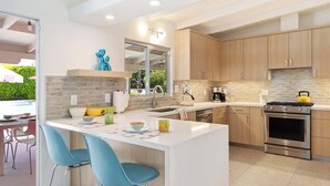 Uma cozinha moderna com ilha central, armários de madeira e eletrodomésticos de aço inoxidável.