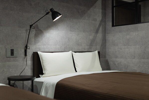 A modern bedroom with a bed, a nightstand, and a desk lamp.