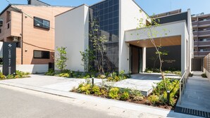 A modern building with a glass facade, a brick exterior, and a landscaped entrance area. - HOTEL All Stay Hakata Kuko Dori (Fukuoka)