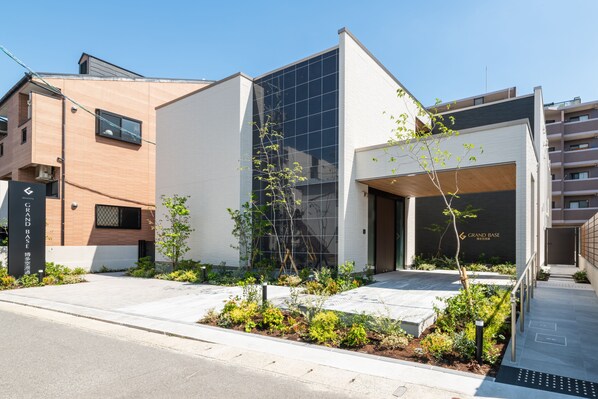Un edificio moderno con facciata in vetro, rivestimento in mattoni e area d'ingresso con aiuole.
