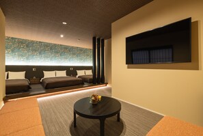 A modern hotel room with a large bed, a small table with a vase, and a large window with curtains.