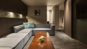 A modern living room with a sectional sofa, a wooden coffee table, and a decorative vase. - HOTEL All Stay Hakata Kuko Dori (Fukuoka)
