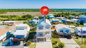 A coastal residential area with houses featuring balconies and a prominent red weather vane. - 5BR + Bonus Bunk Room • Sleeps 14 • 2,900 Sq Ft Beach House • Walk to the Beach (Gulf Shores)