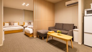 Une chambre d’hôtel comprenant un lit, deux tables de chevet, un canapé, une petite table et un réfrigérateur.