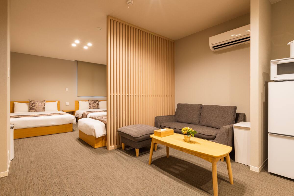 Une chambre d’hôtel comprenant un lit, deux tables de chevet, un canapé, une petite table et un réfrigérateur.