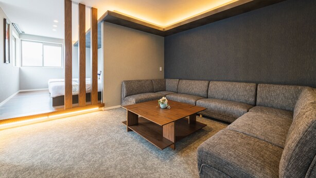 Un salon moderne avec un canapé d’angle, une table basse en bois et une grande fenêtre qui laisse entrer la lumière naturelle.