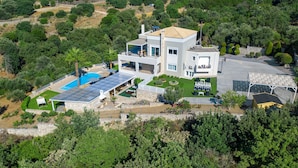 Una casa moderna de dos pisos con piscina, paneles solares y un jardín bien cuidado.