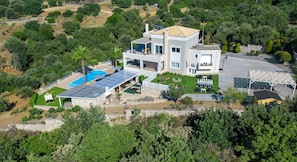 Ein modernes, zweistöckiges Haus mit Swimmingpool, Solaranlage und einem gepflegten Garten.