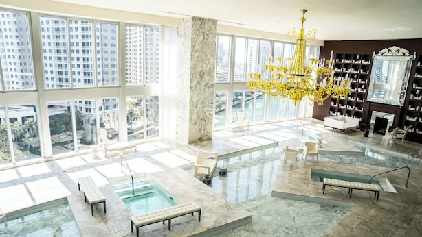 A spacious indoor pool area with multiple seating areas and a large chandelier.