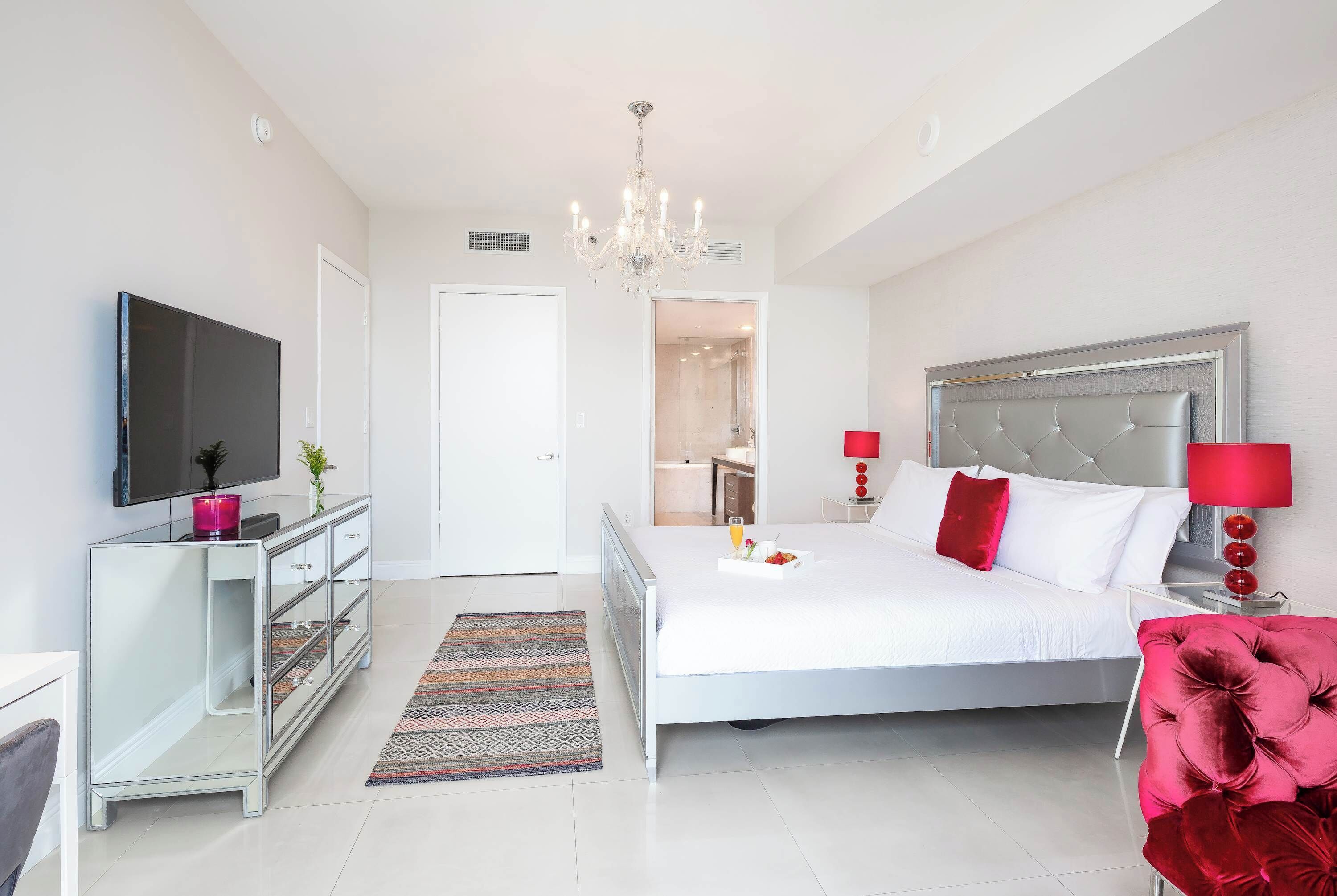 Une chambre moderne avec un grand lit, une télévision, une commode et un lustre.