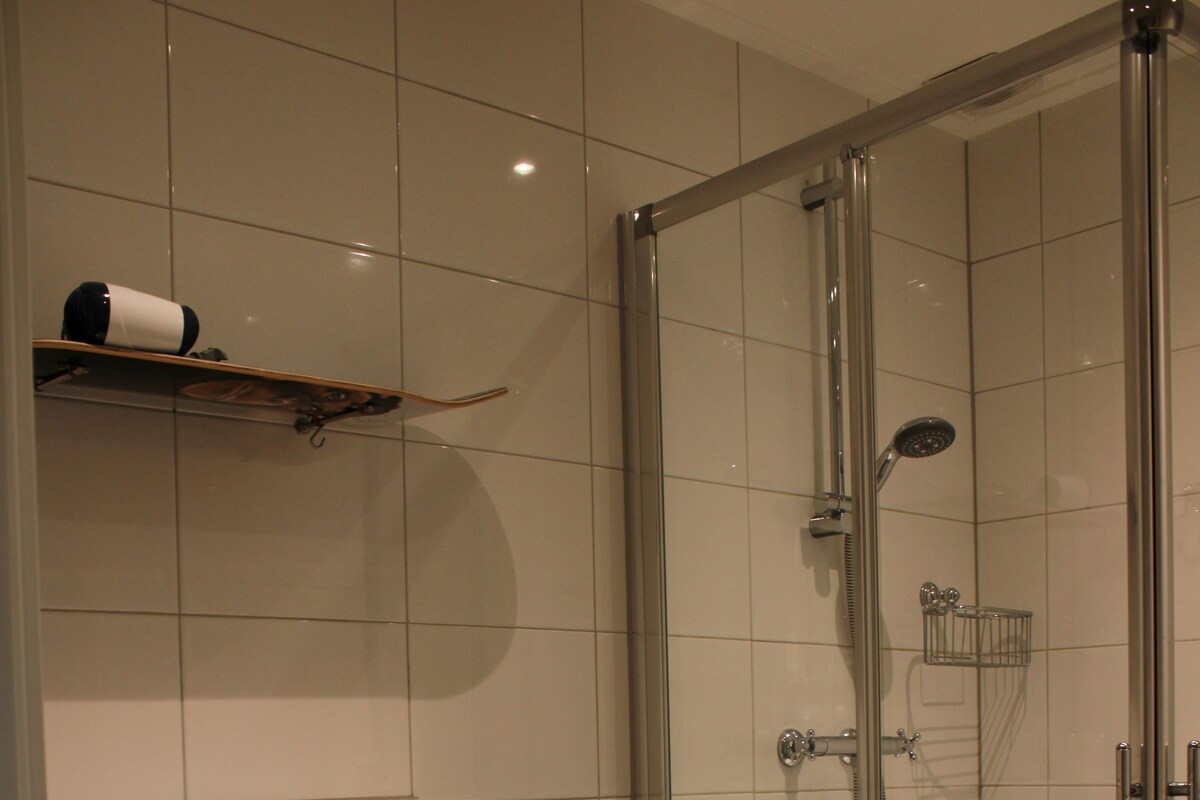 A modern bathroom with a glass-enclosed shower, a toilet, and a towel rack.