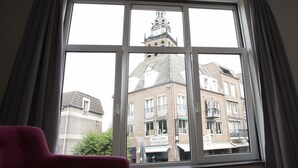 A room with a large window, a red chair, and a green table. - Holt Nijmegen (Nijmegen)