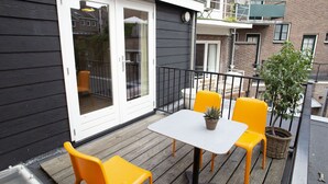 A balcony with a table and chairs, a potted plant, and a view of the building's exterior. - Holt Nijmegen (Nijmegen)