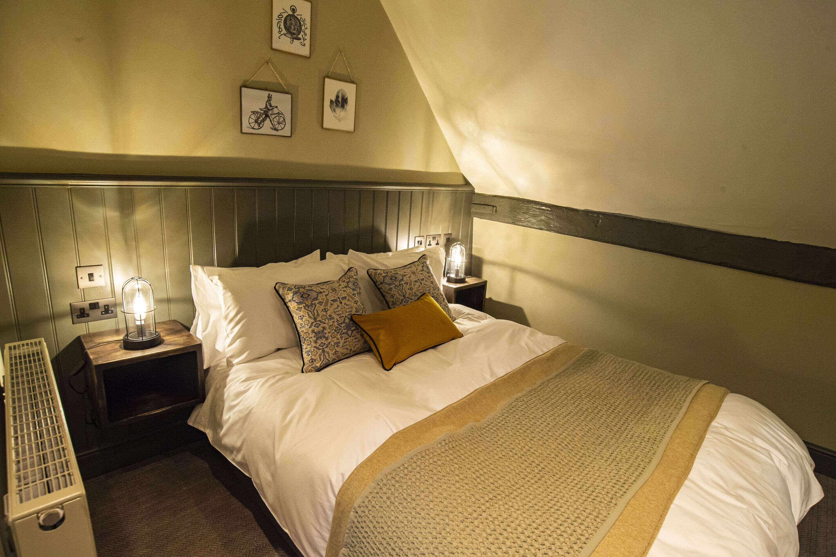 A hotel room with a bed, nightstands, a lamp, and a radiator.