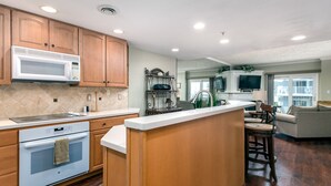 Una cocina con armarios de madera, microondas, horno y una isla central.