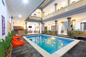 A hotel lobby with a central pool, multiple floors, and a reception area. - Krisnayogi Homestay (Canggu)