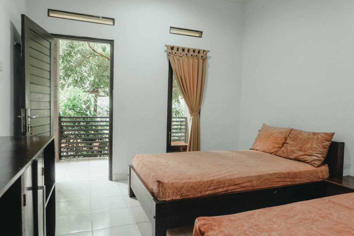 A bedroom with two beds, a wardrobe, and a window with curtains.