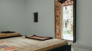 A room with a bed, a small table, and a window with curtains. - Hotel Diana 2 (Denpasar)