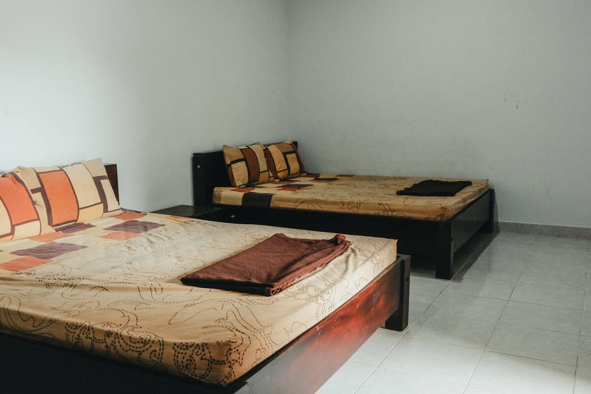 A room with two single beds, each with a wooden frame and a patterned bedspread.