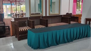 A room with a long table covered with a teal tablecloth, wooden benches with striped cushions, and a large mirror on the wall. - Penginapan Pendopo Kasih (Semin)