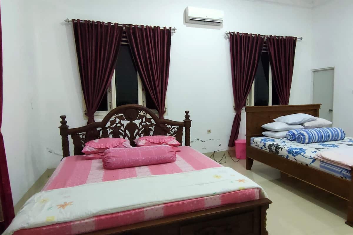 A bedroom with two wooden beds, each with a headboard, and a large mirror on the wall.