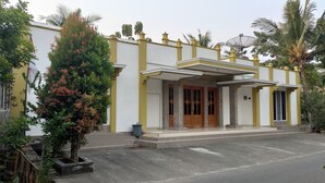 A two-story building with a yellow and white facade, large wooden doors, and a covered entrance. - Penginapan Pendopo Kasih (Semin)