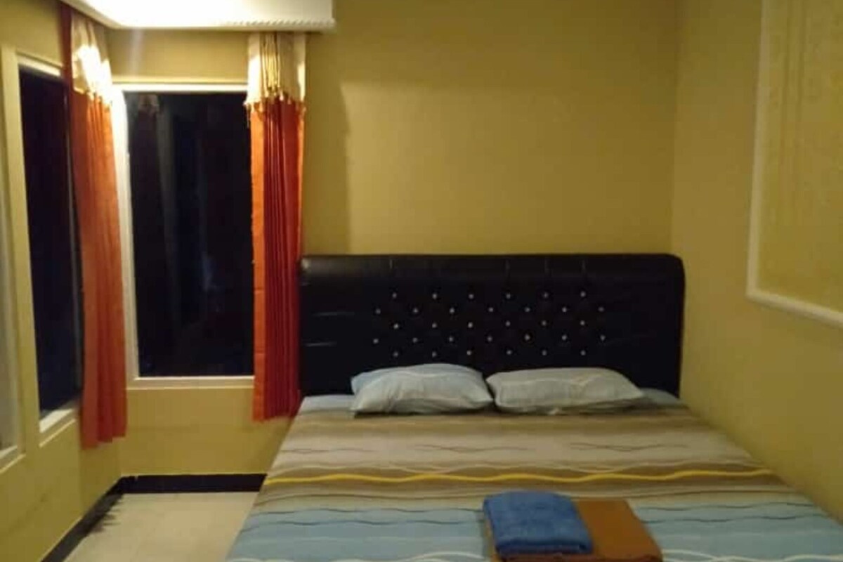 A bedroom with a bed, curtains, and a window.
