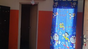 A room with a blue curtain featuring cartoon characters, a door, and an air conditioning unit on the wall. - Lautze Residence (Jakarta)