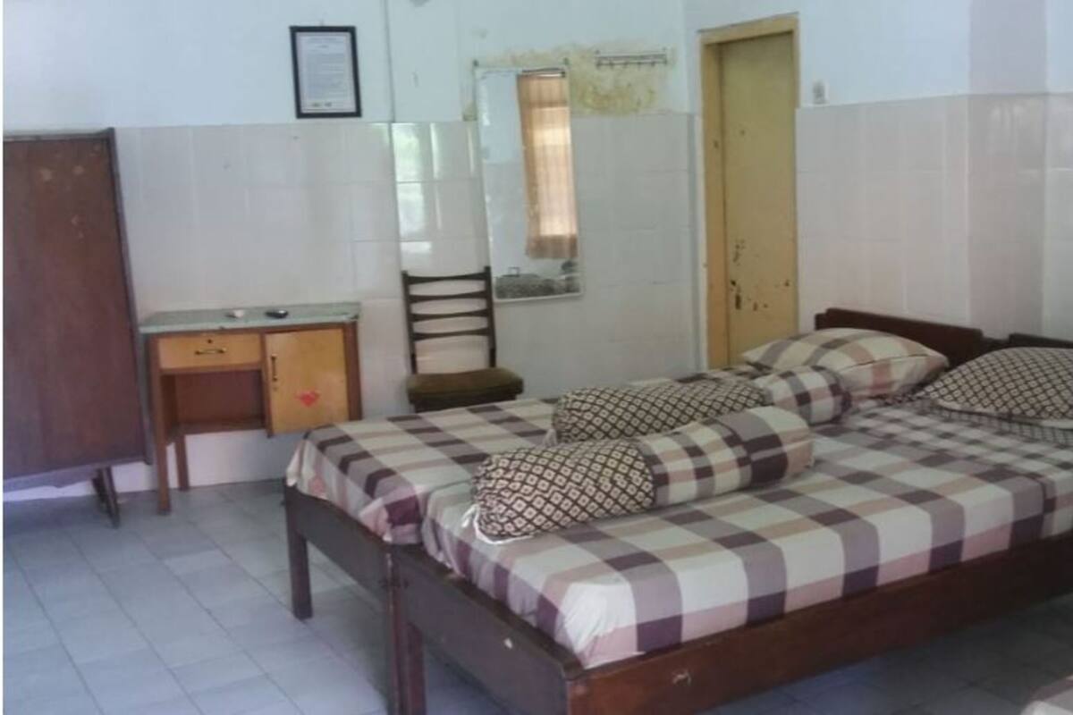A bedroom with a double bed, a wooden desk, and a chair.