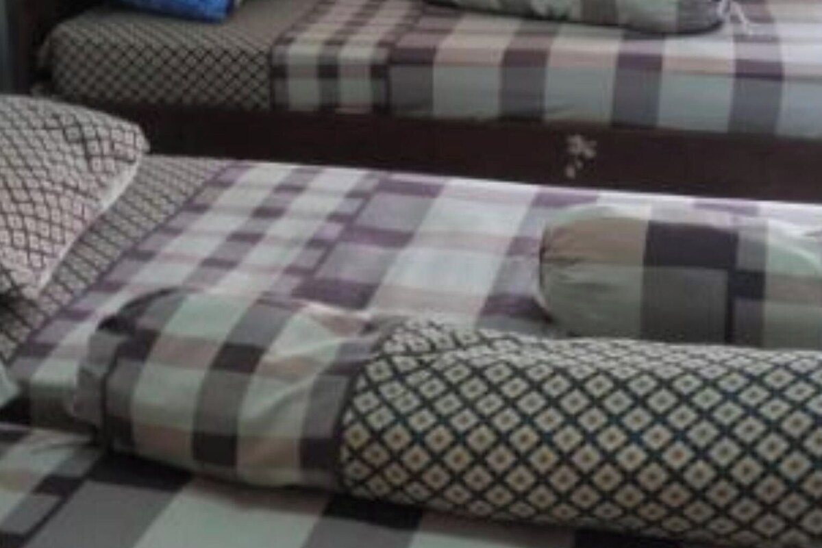 A room with two beds, each with patterned bedding and pillows.