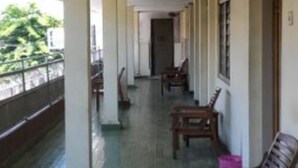 A covered corridor with wooden benches, columns, and a tiled floor. - Hotel Indah Syariah (Surabaya)