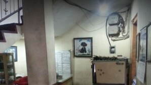 A compact kitchen with a refrigerator, a chair, and a wall-mounted air conditioner. - Hotel Indah Syariah (Surabaya)